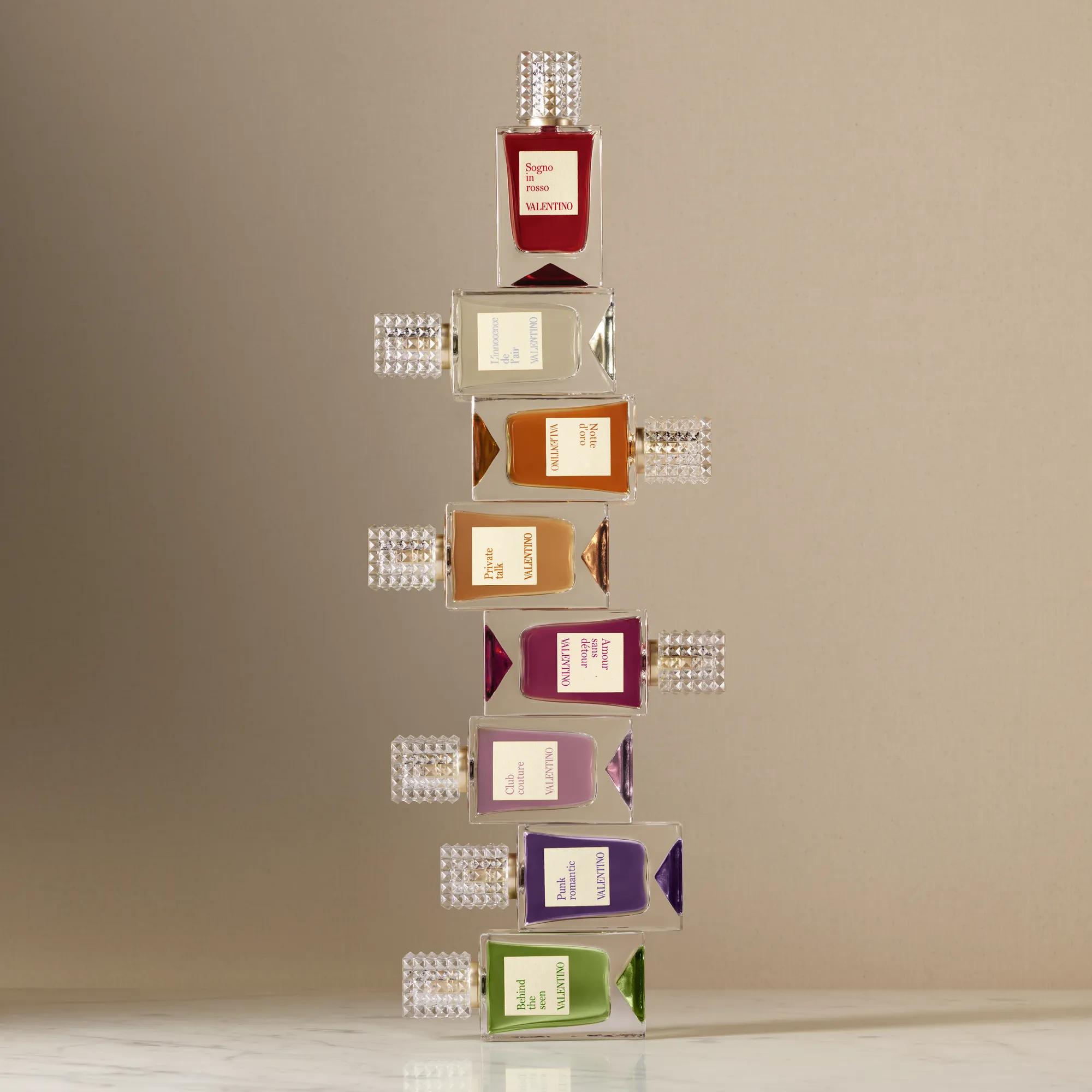 Eight colorful perfume bottles artistically stacked against a neutral background