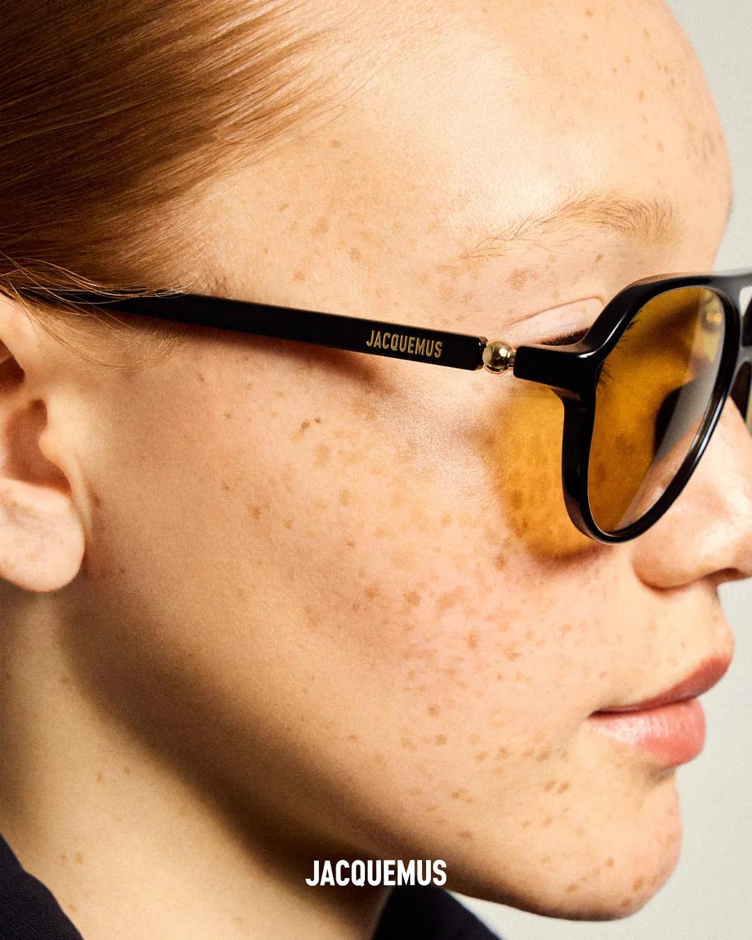 Close-up of a freckled person wearing black sunglasses with amber-tinted lenses