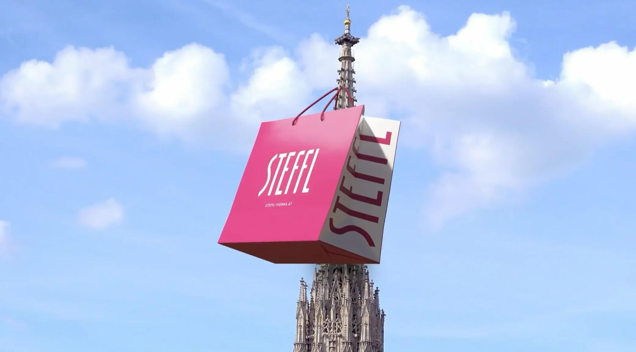 Pinke STEFFL-Einkaufstasche schwebt vor dem Stephansdom in Wien vor blauem Himmel